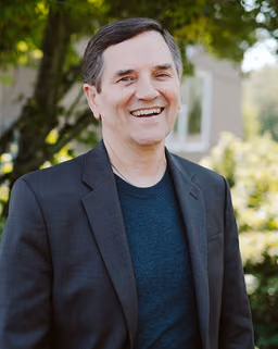 Rick L. Jackson, MD, outdoors in a dark jacket, smiling toward the camera.